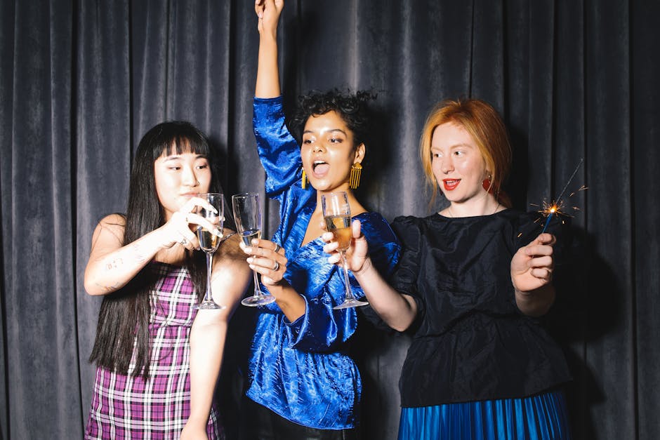 Three women celebrating with wine and sparklers in a festive indoor setting